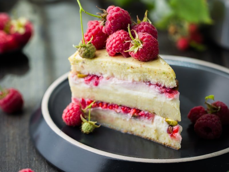 Layered raspberry mousse cake on dark plate with fresh berries