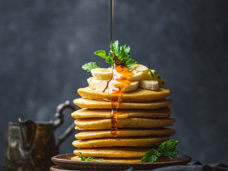Stack of golden pancakes with maple syrup pour at a brunch event