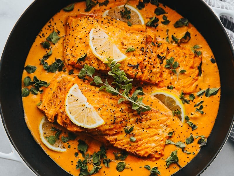 Hot lunch buffet salmon dish in cream sauce with herbs and lemon