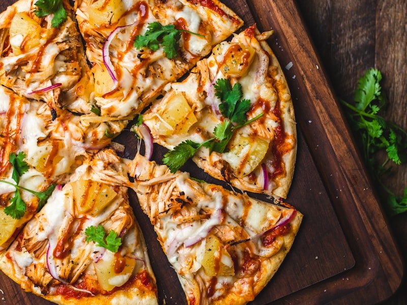 Wood-fired pizza on a rustic board with cilantro garnish