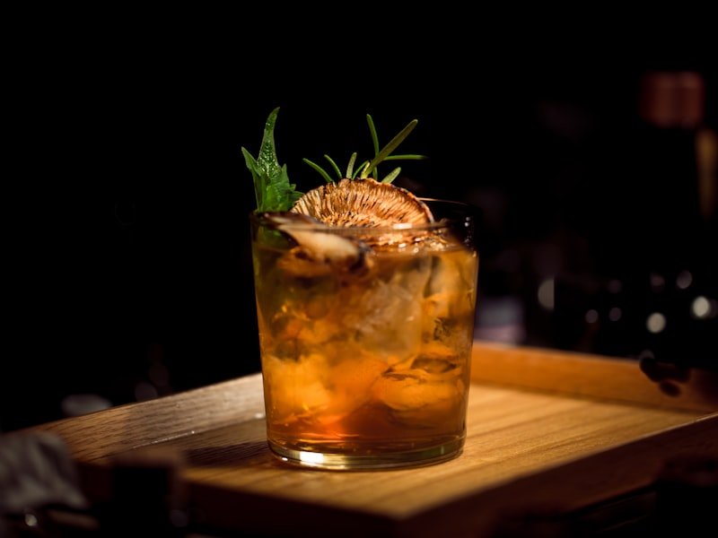 Old-fashioned cocktail with rosemary garnish on a wood bar surface